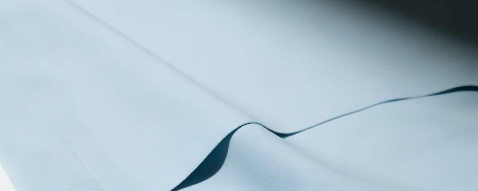 Close-up of a light blue silky recycled nylon fabric on a white surface