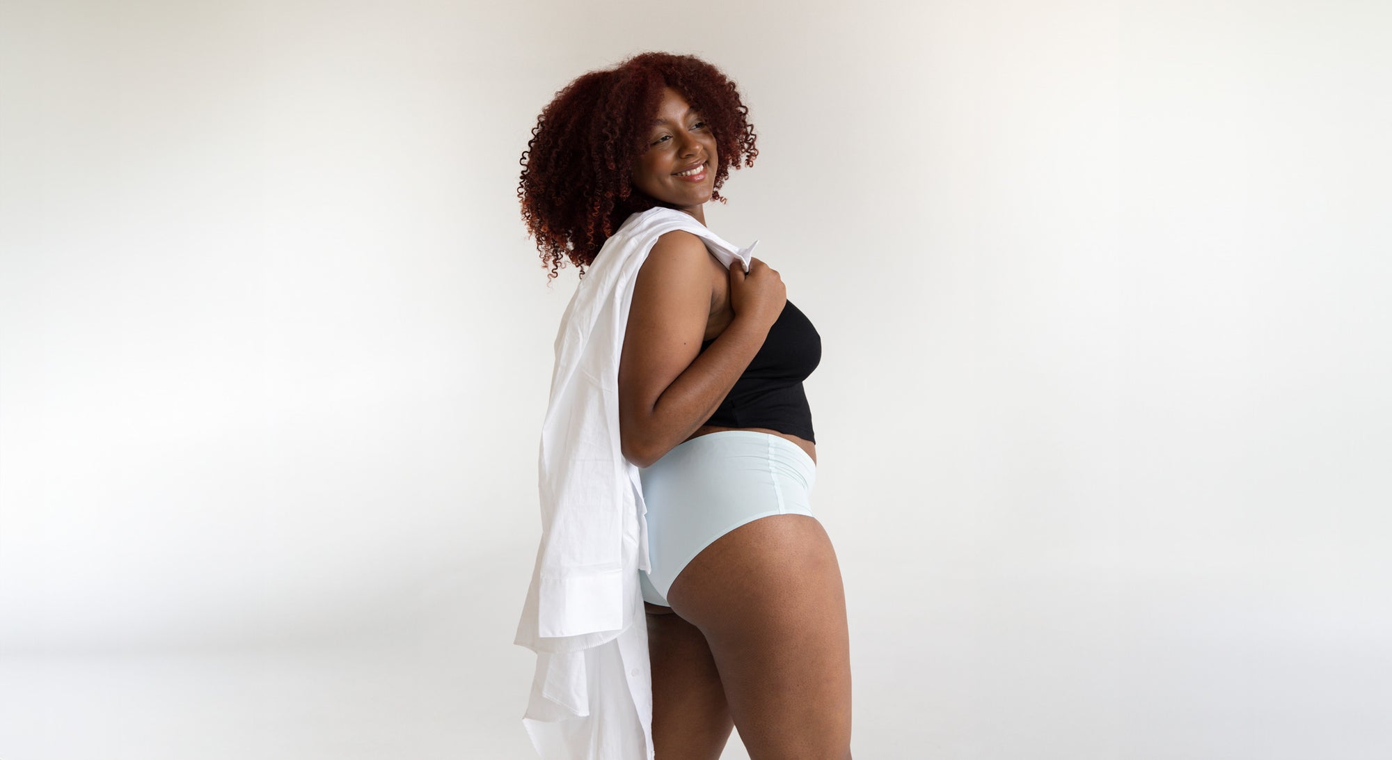 Woman wearing a black top and white light blue comfortable seamless undies that don't ride up or cause wedgies